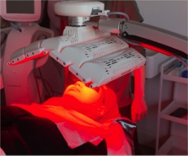 Client beneath an LED light therapy device at Kozie Skin Clinic